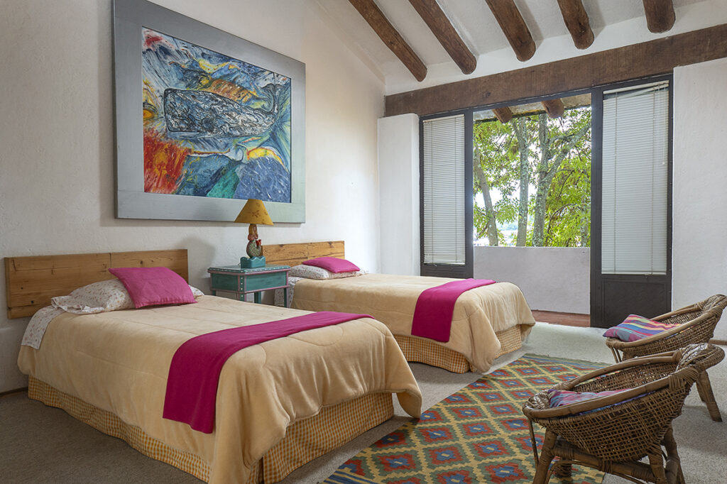 recamara doble, camas vestidas y sillas de mimbre  en casa en Valle de bravo, renta vacacional, fotografía profesional